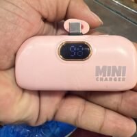 pink mini capsule power bank charger  with a built-in plug connector and a digital percentage display.